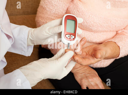 Krankenschwester nimmt Test für Zucker im Blut der älteren Frau zu Hause. Stockfoto