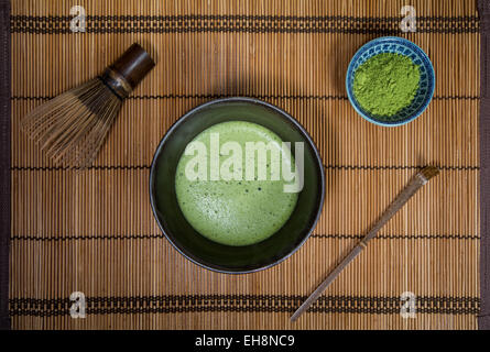 Schüssel mit Matcha mit einem Chasen einen Chashaku und eine Schüssel mit Matcha-Pulver auf einem Tischset Stockfoto