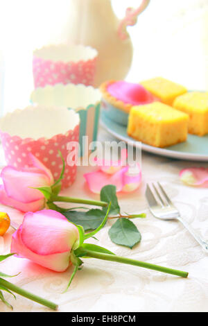 Rosa Rosen und frische Kuchen auf dem Tisch in weiches Licht Stockfoto