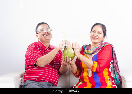 2 indische Senioren verheiratet Paare sitzen Sofa trinken Kokosnuss Früchte Stockfoto