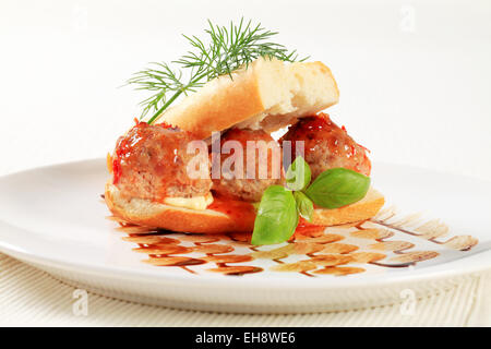 Stangenbrot mit Frikadellen gefüllt und garniert mit roter sauce Stockfoto