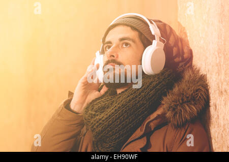 ein junger Mann hört Musik in einem städtischen Bild des modernen Lebens, warmen Tönen Stil getönt