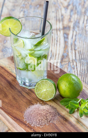 Glas mit Mojito-Cocktail und seine Inhaltsstoffe auf rustikalen Holztisch Stockfoto