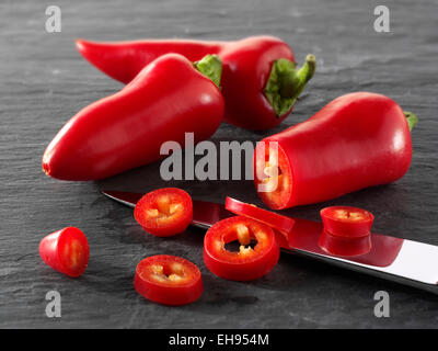 Frische rote Chilis ganze & Cut auf schwarzem Hintergrund, komponierte Anordnung Stockfoto