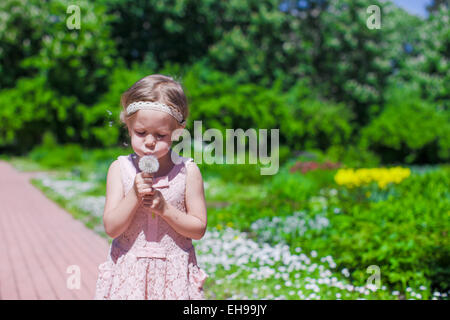 Kleines Mädchen bläst einen Löwenzahn im freien Stockfoto