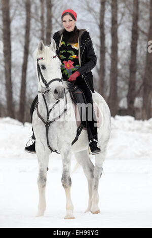 Hübsche Frauen geht auf das graue Pferd im Winterdienst Stockfoto