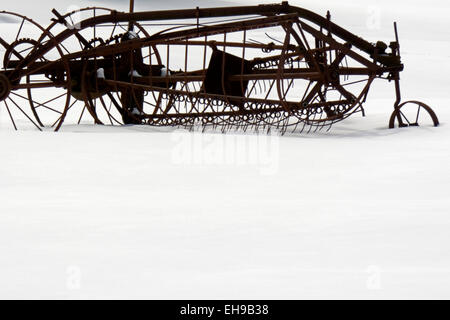 Ein antikes Stück von Landmaschinen sitzt im Schnee verworfen. Stockfoto