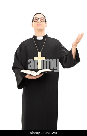Vertikale Schuss von einem jungen männlichen Priester zu Gott zu beten und halten eine Bibel isoliert auf weißem Hintergrund Stockfoto