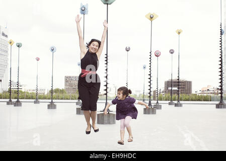 Mutter und Tochter springen vor Whimiscal Skulpturen, La Défense, Paris, Frankreich Stockfoto