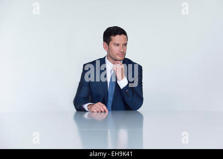 Geschäftsmann, sitzen am Tisch, wegschauen in Gedanken Stockfoto