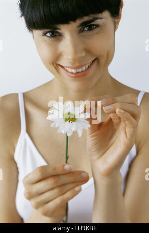 Junge Frau zupfen Blütenblätter von Blumen, Lächeln, Porträt Stockfoto