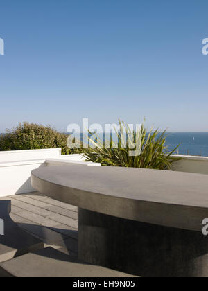 Steintisch und Bank auf Terrasse mit Meer Blick außerhalb Wohnhaus, Marine Drive, UK Stockfoto