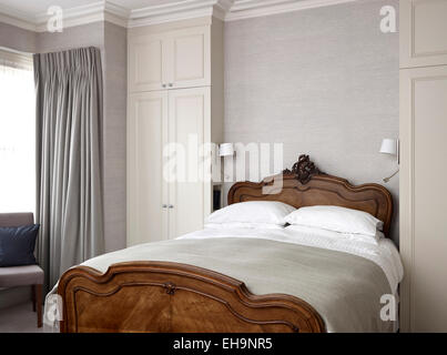 Reich verzierte hölzerne Bettgestell mit passenden Lampen im Schlafzimmer des Fernhurst Road Home, UK Stockfoto