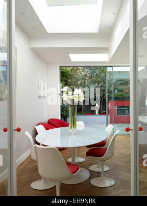 Blick zum modernen runder Tisch mit roten Stühlen und Außenbereich in Chesilton Road Home, UK Stockfoto