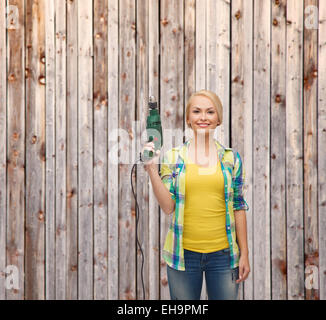 lächelnde Frau mit Bohrmaschine Stockfoto