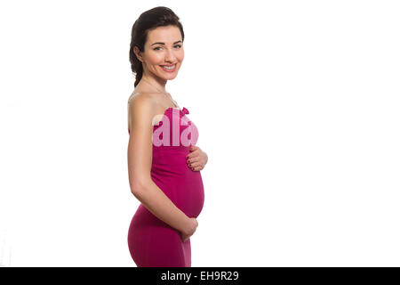 Junge kaukasischen lächelnd schwangere Dame in rosa Kleid berühren Bauch im Profil isoliert auf weißem Hintergrund Stockfoto