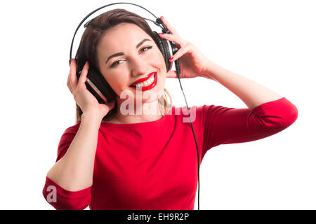 Mädchen Langarm T-shirt tragen rote Lippenstift berühren große Kopfhörern Musik hören lächelnd und Blick auf Kamera isolat Stockfoto