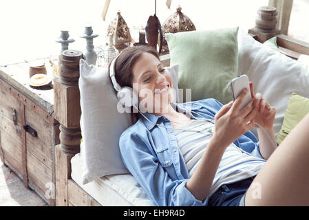 Junge Frau entspannend mit Smartphone und Kopfhörer Stockfoto
