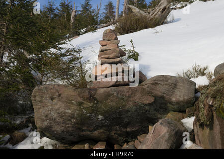 Angemessene Nahaufnahme von stehenden Steinen mit einem Hintergrund von Schnee und Pinien und einem Hauch von einem blauen Winterhimmel. Stockfoto