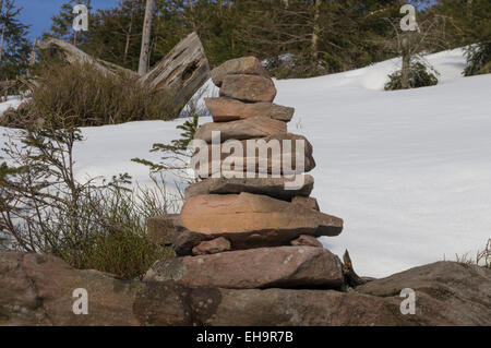 Nahaufnahme von stehenden Steinen mit einem Hintergrund von Schnee und Pinien und einem Hauch von einem blauen Winterhimmel. Stockfoto