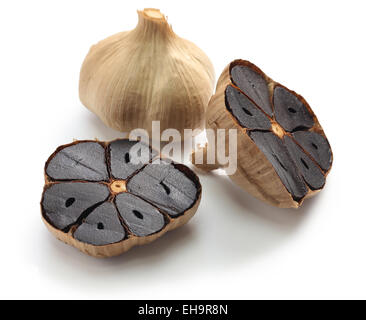 schwarzer Knoblauch Zwiebeln und Knoblauchzehen auf weißem Hintergrund Stockfoto