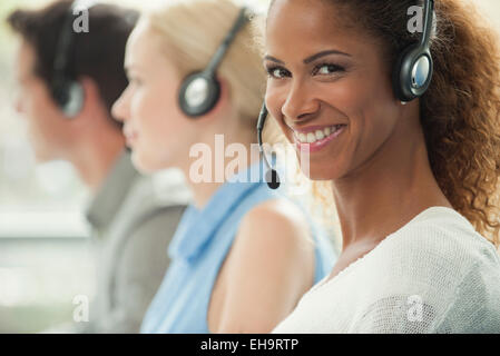 Frau arbeitet im Call-Center, fröhlich lächelnd Stockfoto