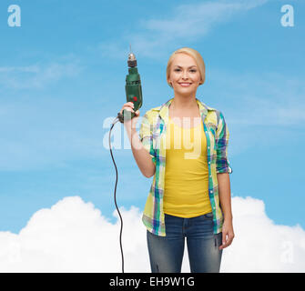 lächelnde Frau mit Bohrmaschine Stockfoto