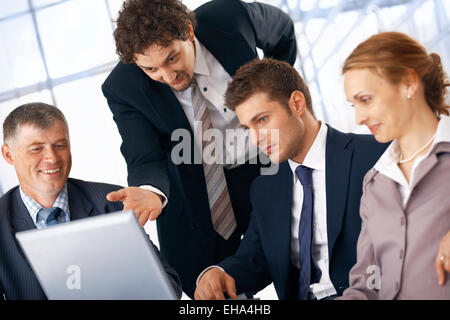 Business-Mann zeigt etwas am Laptop an seine Kollegen. Stockfoto
