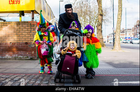 Donnerstag, 5. März 2015 geht ein Ultra-orthodoxe jüdische Mann mit seinen Kindern in Kostüm gekleidet, die jüdischen Purim-Urlaub in Stamford Hill Gegend von London zu feiern. Stockfoto