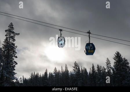 Seilbahnen im Skigebiet auf Bäume vor stürmischen Wolken und Himmel bewegen Stockfoto