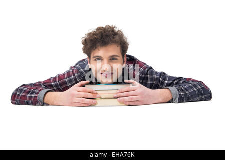 Lächelnde junge Mann auf dem Tisch liegend mit Bücher Stockfoto