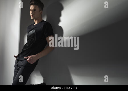 Schöner schlanker Mann an die Wand gelehnt Stockfoto