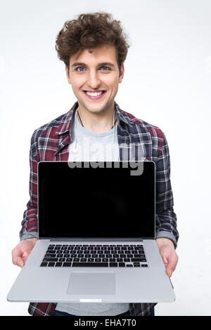 Lächelnder junge Mann zeigt Laptopbildschirm auf grauem Hintergrund Stockfoto