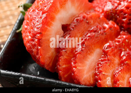 Einzelne wohlgeformte Erdbeere mit Blätter in Gruppe von Erdbeeren. Stockfoto