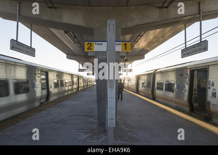 Merrick, New York, USA. 9. März 2015. Ein nonstop Zug Heads Eastbound, auf der linken Seite, während ein westwärts Zug nach Penn Station auf der rechten Seite, gestoppt und hat seine Türen für die Passagiere auf der erhöhten Plattform der Merrick Long Island Rail Road LIRR Station Teil des Ortsverbandes Babylon Zug während der Hochphase der Abend pendeln, öffnen den ersten Wochentag pendeln nach Sommerzeit begann. Bildnachweis: Ann Parry/ZUMA Draht/Alamy Live-Nachrichten Stockfoto