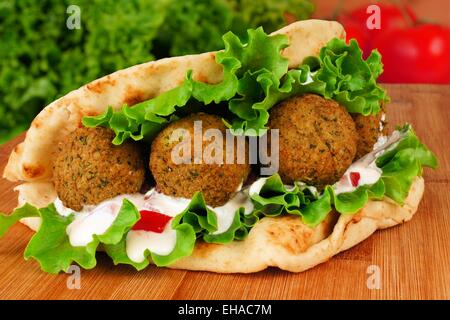 Falafel mit Gemüse und Tzatziki Sauce in Pita Brot Nahaufnahme auf Holztisch Stockfoto