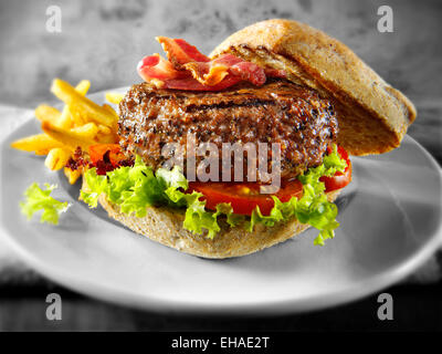 Rindfleisch-Burger mit Speck in einem Brötchen mit Salat und Pommes chips Stockfoto