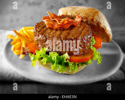 Rindfleisch-Burger mit Speck in einem Brötchen mit Salat und Pommes chips Stockfoto