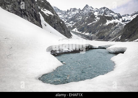 Stream durchbricht Schneedecke in der Pré de Madame Carle, Nationalpark Ecrins, Französische Alpen. Stockfoto