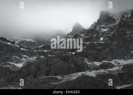 Schwarz und weiß: gezackte Gipfel in dicke Wolke auf der Südseite des Berges Barre des Ecrins, Französische Alpen. Stockfoto