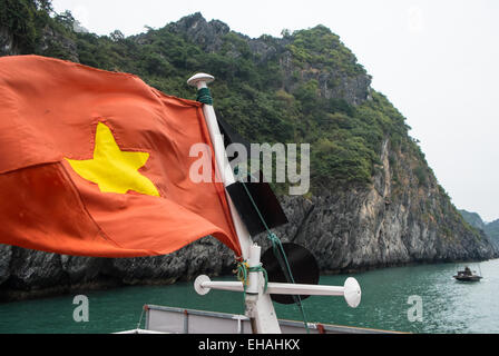 Vietnamesische Flagge oben auf touristischen Boot unter Kalkstein Karst im Cat Ba Nationalpark, Ha long, Halong Bucht, Vietnam Stockfoto