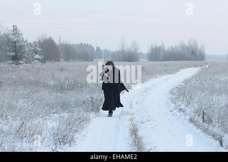 Samurai trägt einen Kimono in einem Winter Feld laufen gekleidet in schwarz, frost Stockfoto