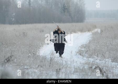 Samurai trägt einen Kimono in einem Winter Feld laufen gekleidet in schwarz, frost Stockfoto