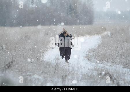 Samurai trägt einen Kimono in einem Winter Feld laufen gekleidet in schwarz, frost Stockfoto