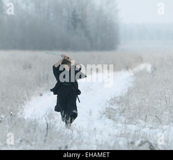 Samurai trägt einen Kimono in einem Winter Feld laufen gekleidet in schwarz, frost Stockfoto