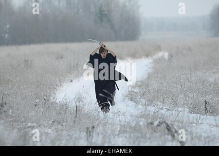 Samurai trägt einen Kimono in einem Winter Feld laufen gekleidet in schwarz, frost Stockfoto