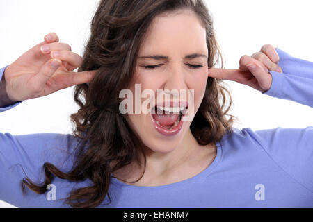 Frau mit ihren Fingern in den Ohren Stockfoto