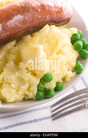 Kartoffelbrei mit zerlassener Butter, Wurst und Erbsen. Stockfoto