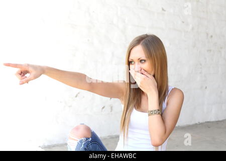 Lächelnde Frau zeigt auf jemanden Stockfoto