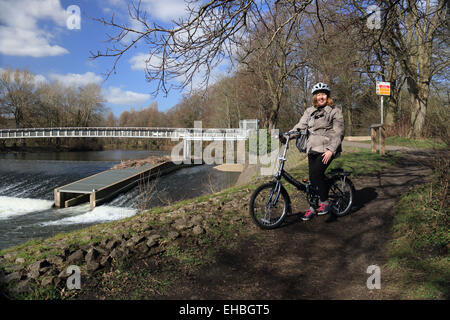 Frau mit kleinen Fahrrad von Fluss-Wehr und Steg. Stockfoto